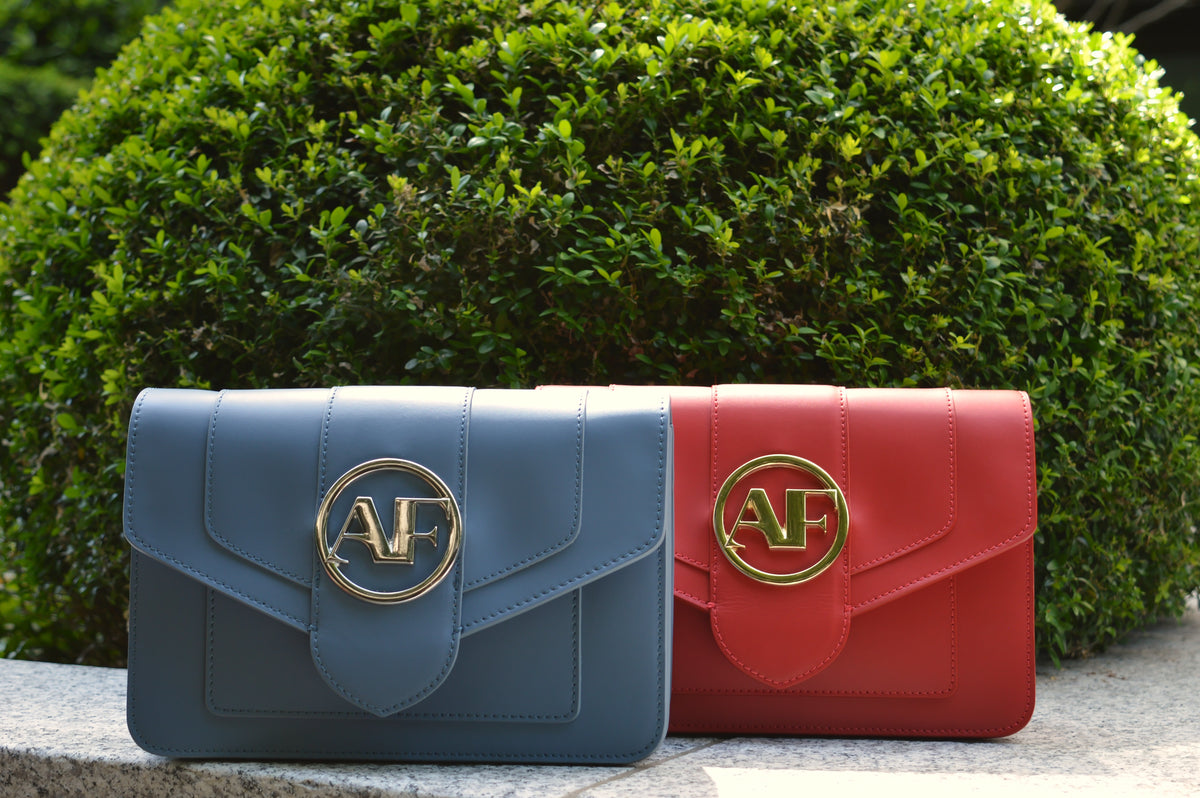 Brera, crossbody bags in blue and red smooth Italian Ruga leather – side by side outdoors