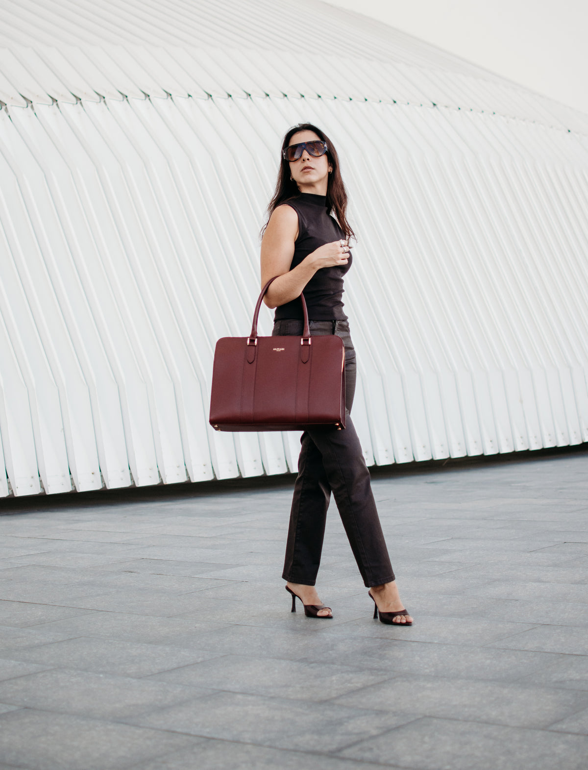Alinari burgundy leather tote carried by hand, full-length photo in a white arcade