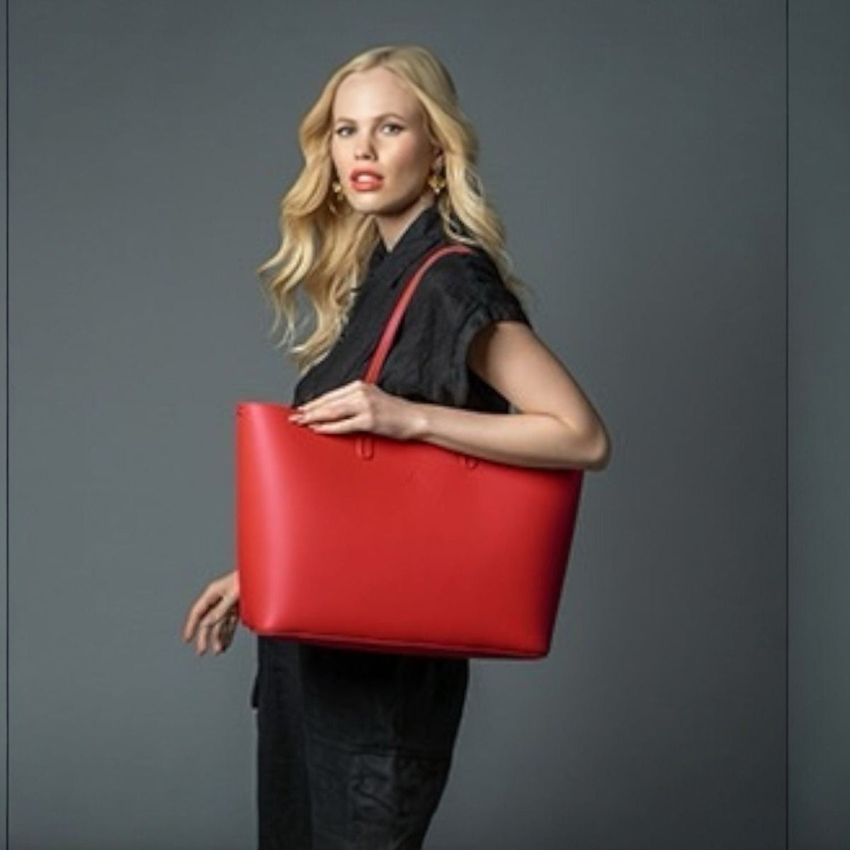 Woman carrying the Maxima Tote, a red smooth Italian leather laptop bag