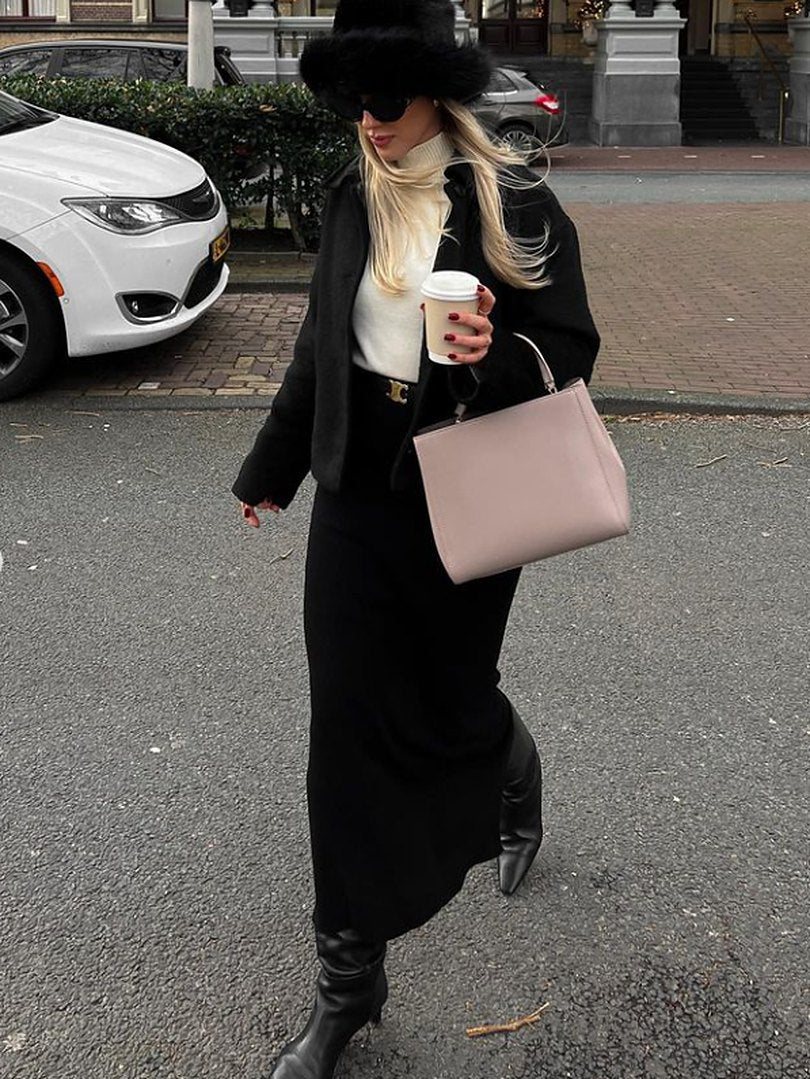 Woman in a black coat carrying a blush pink leather handbag