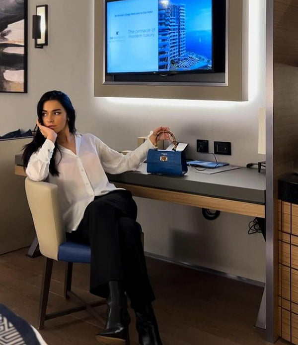 Woman at a desk with a blue Italian leather handbag