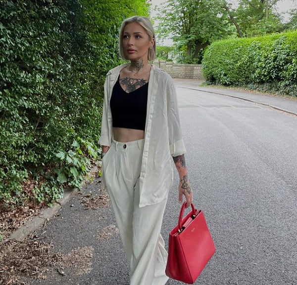 Woman in a white trouser suit carrying a red leather top-handle bag