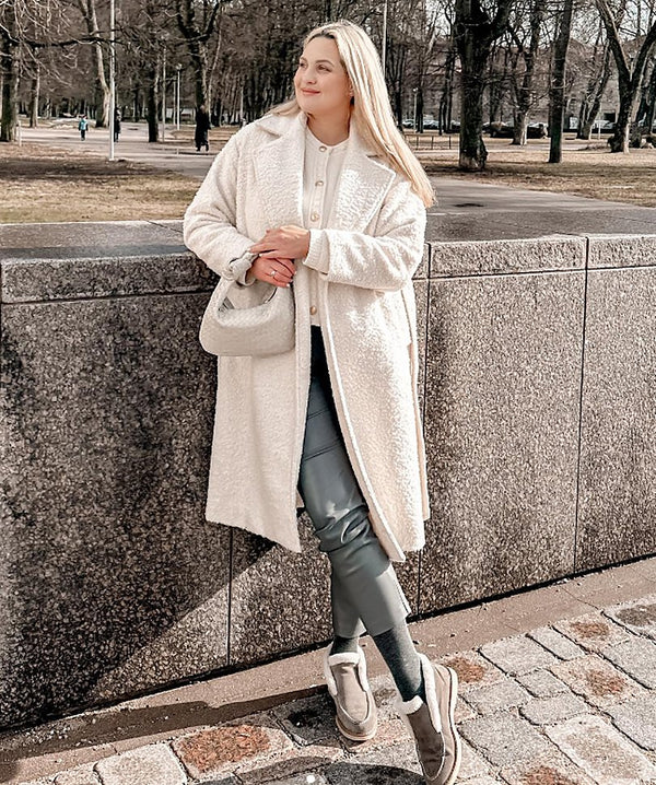 Woman in a white coat with a white Italian leather shoulder bag