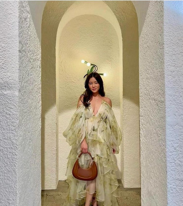 Woman in a floral gown holding a small tan Italian leather bag