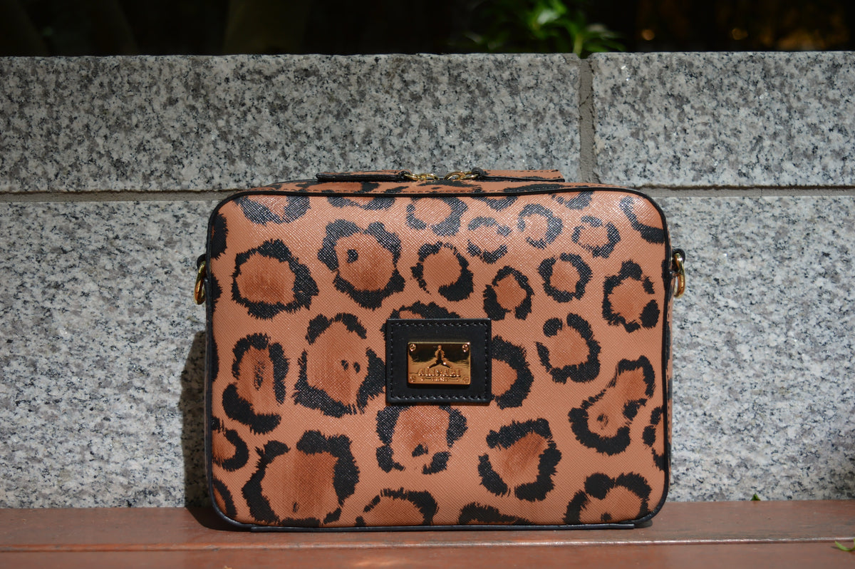 Flavia, crossbody bag in leopard-print Italian Ruga leather – front view outdoors, showing the print and logo plate