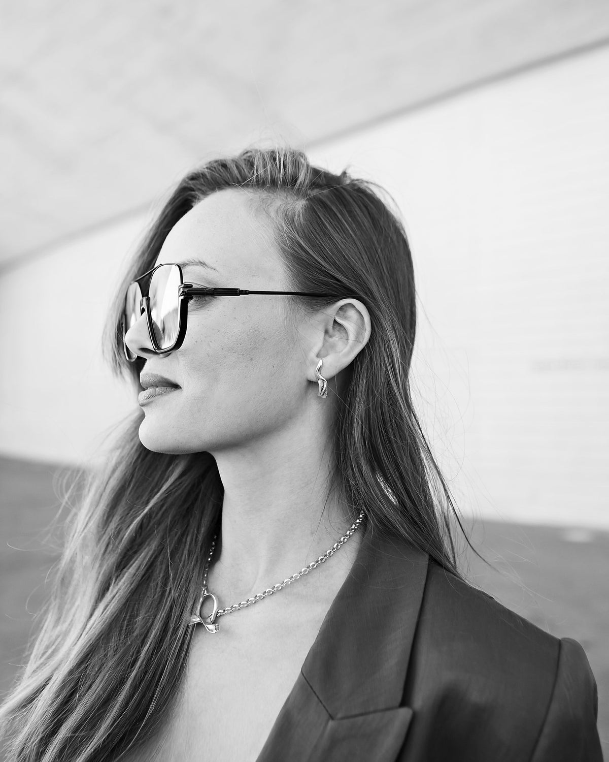 Black and white side profile with Toscana sunglasses and a silver chain necklace