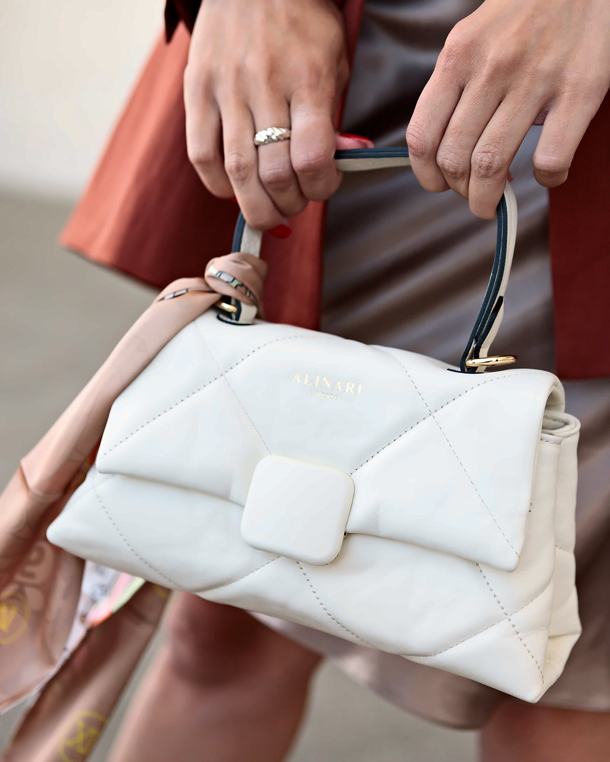 Alita, shoulder bag in white quilted Italian leather – close-up of the top handle, held with a rust linen blazer